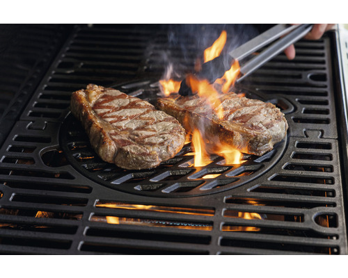 Två biffar grillas på en grill med lågor