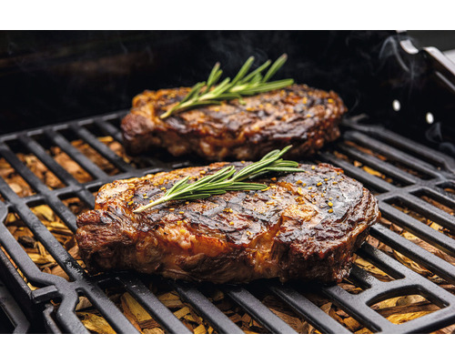 Två biffar med rosmarin på en grill