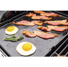 Bacon och stekta ägg tillagas på en grillplatta.