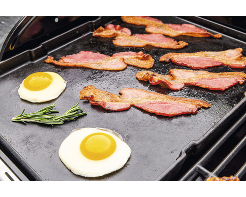 Bacon och stekta ägg tillagas på en grillplatta.