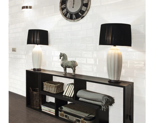 Vardagsrum med svarta hyllor, bordslampor och vita väggplattor i retrostil