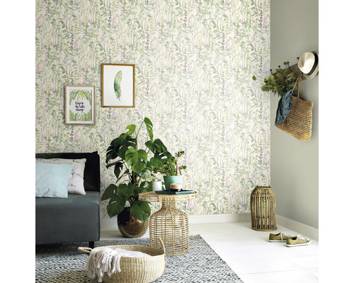 Vardagsrum med soffa, sidobord, krukväxter, dekoration och tapet med växtmönster.
