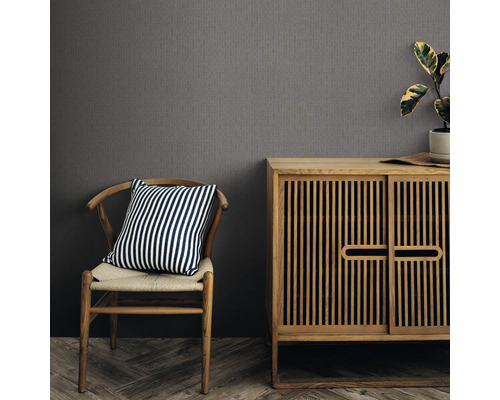 Inredningsexempel med en grå strukturtapet, ett träskåp och en stol med en randig kudde.