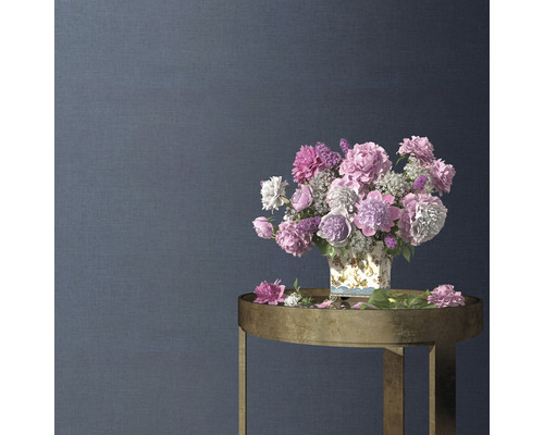 Dekorativ blomsterarrangemang i en vas på ett sidobord framför en strukturerad vägg