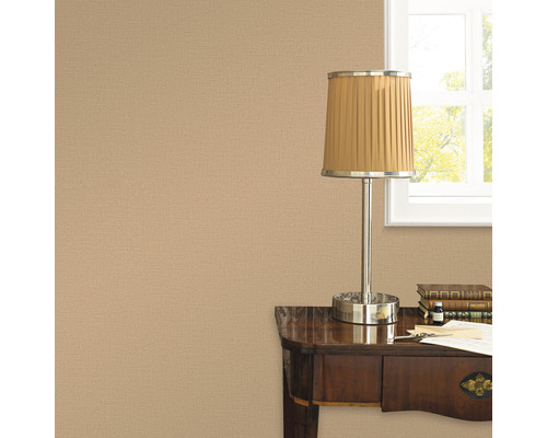 Närbild av en beige textilväggbeklädnad i ett arbetsrum med bordslampa och skrivbord
