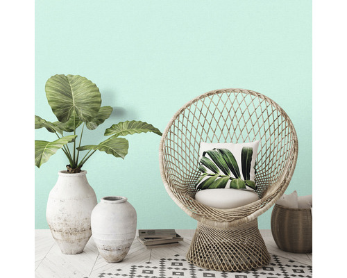 Dekorativ scen med rottingfåtölj, växter i vaser och mönstrad matta