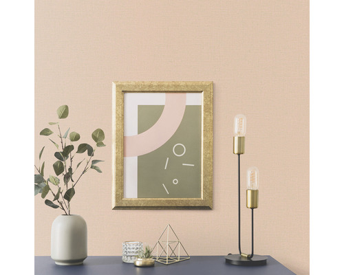 Vardagsrum med en bild i en guldram, en lampa och en vas med växter på en byrå.