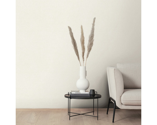Dekorativa fjädrar i en vit vas på ett svart sidobord bredvid en soffa