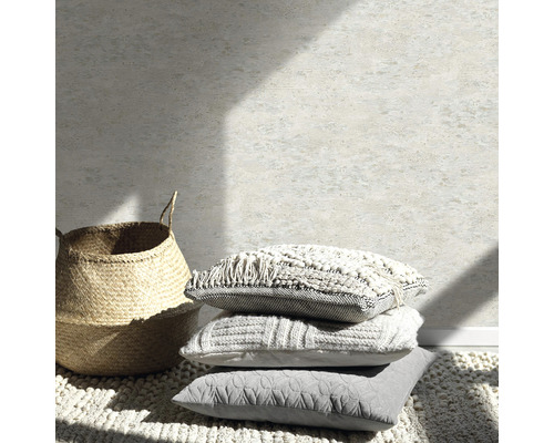 Dekorativt stilleben med kuddar, matta och korg framför en vägg