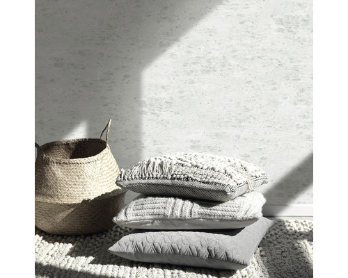 Dekorativ scen med staplade kuddar, korg och matta för inredning.