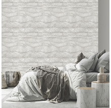 Sovrum med säng framför en ljus tapet med vågmönster