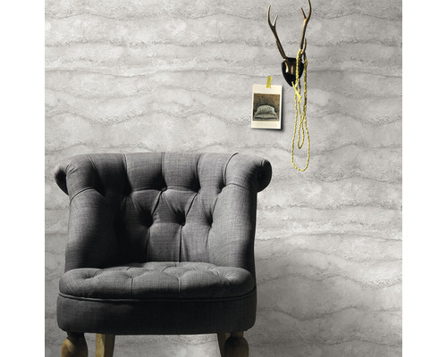 Grå fåtölj framför en tapet med vågmönster, med ett horn ovanför