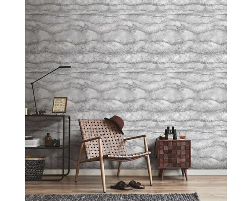 Vardagsrum med mönstrad tapet, fåtölj och sidobord.