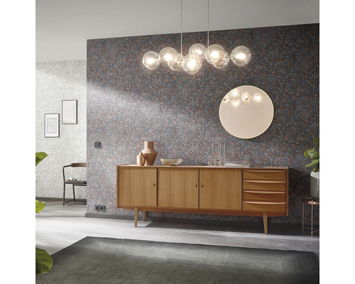 Vardagsrum med byrå, lampa och mönstrad tapet