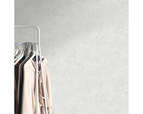 Vägg med abstrakt mönster bredvid en klädställning med kläder.