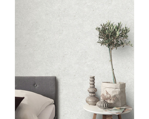 Scen med säng, sidobord, krukväxt och mönstrad tapet