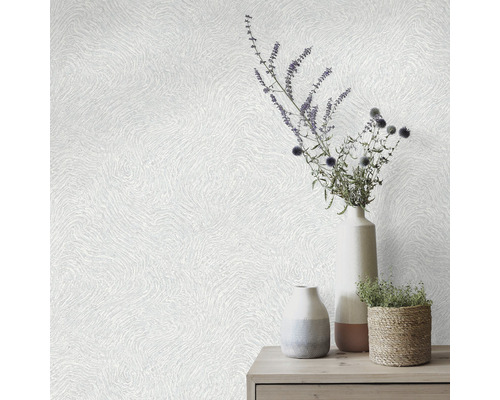 Dekorativ tapet med vågigt mönster och vaser med blomsterarrangemang på ett bord