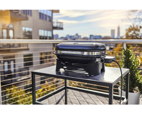 Weber Lumin elektrisk grill på ett bord utomhus med utsikt över staden
