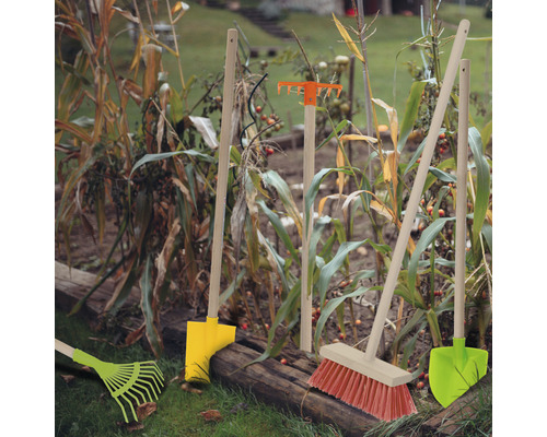 Trädgårdsredskap som räfsor, kvastar och spadar i rabatten