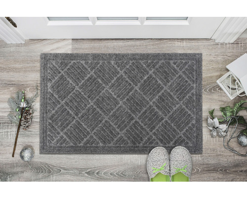 Grå dörrmatta med geometriskt mönster framför en dörr