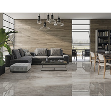 Vardagsrum med grått golvkakel, trävägg, grå soffa och matbord med stolar