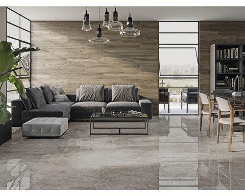 Vardagsrum med grått golvkakel, trävägg, grå soffa och matbord med stolar