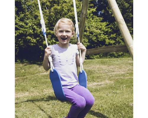 Flicka gungar på en blå gunga i trädgården