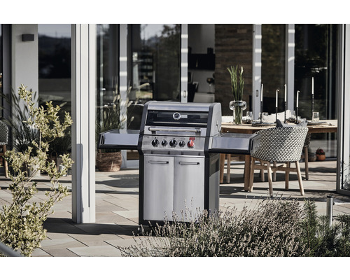 Gasolgrill i rostfritt stål med fyra brännare och sidobord på terrassen