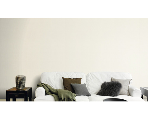 Vardagsrum med vit soffa, kuddar och sidobord mot en vägg