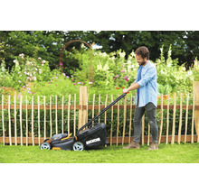 Man klipper gräsmattan med en WORX gräsklippare i trädgården.