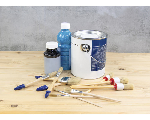 Färghink, lackflaska och penslar på ett träbord