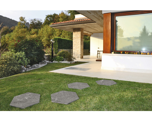 Trädgårdsgång av sexkantiga stenplattor i gräsmattan framför ett modernt hus.