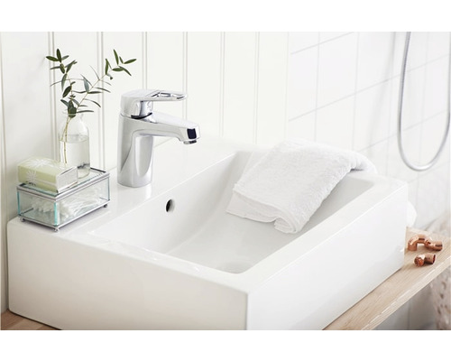 Modern handfat med blandare, handduk och dekoration i badrummet.