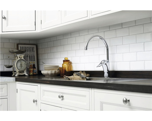 Köksscen med diskho, armatur, disk och köksvåg framför en vit kakelvägg