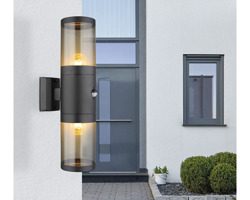 Modern utomhusvägglampa med två lampor och rörelsedetektor framför en ytterdörr