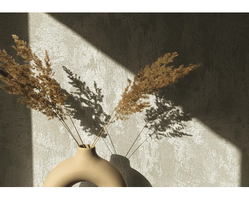 Dekorativa torkade blommor i en keramisk vas framför en vägg med skuggor