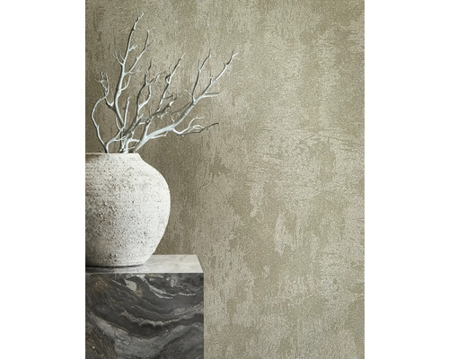 Närbild av en väggtapet med en reliefartad struktur bredvid en dekorativ vas och grenar