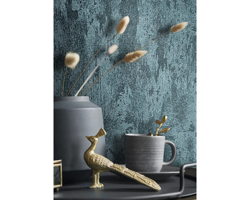 Dekorativt stilleben med tapet, gyllene påfågelfigur, kopp och vas