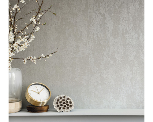 Närbild av en väggbeklädnad med en abstrakt textur, kombinerat med en vas, en klocka och en lotusblomma på en hylla