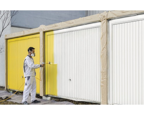 Man sprutar garageport med färgsprutpistol