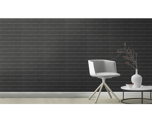 Rumsvy med svarta kakelplattor på väggen, en stol och ett bord