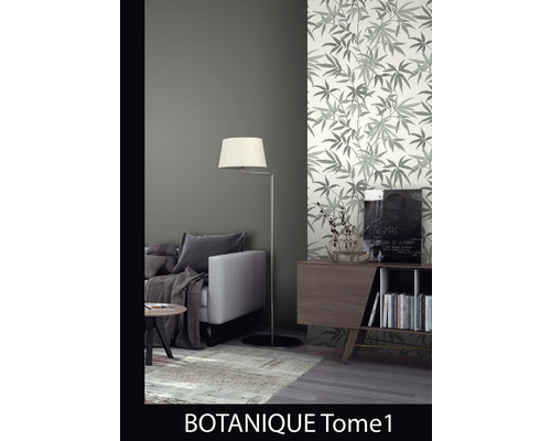 Vardagsrum med soffa, golvlampa och en vägg med tapet med bladmönster.