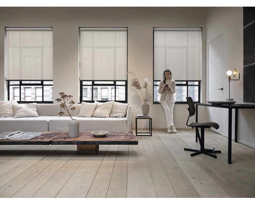 Vardagsrum med tre fönster och neddragna rullgardiner för insynsskydd och solskydd