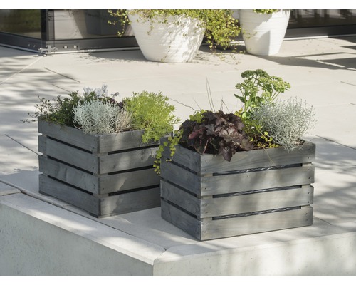 Två grå planteringslådor i trä med plantering