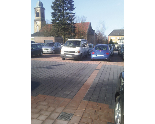 Parkeringsplats med stenlagd yta och parkerade bilar