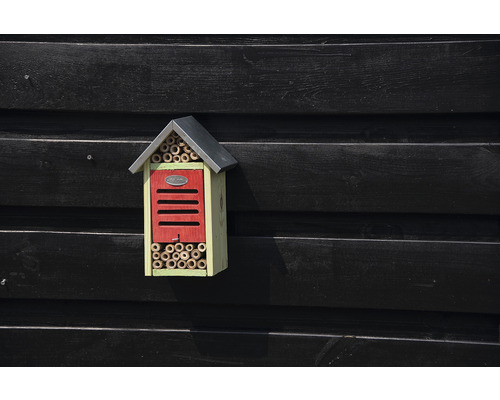 Insekthotell med bamburör och tak på en trävägg