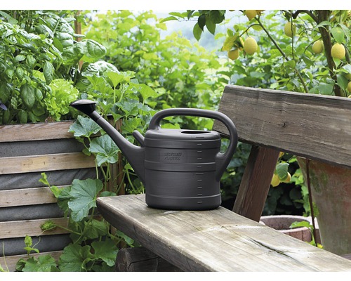 Vattenkanna av plast på en träbänk i trädgården