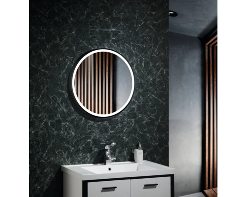 Badrum med rund spegel, tvättställ och kran mot en mönstrad vägg