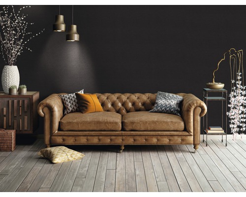 Vardagsrum med brun lädersoffa i Chesterfield-stil, trägolv och dekorativa element