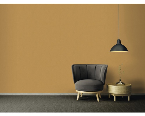 Vardagsrum med fåtölj, sidobord och hänglampa framför en enfärgad vägg